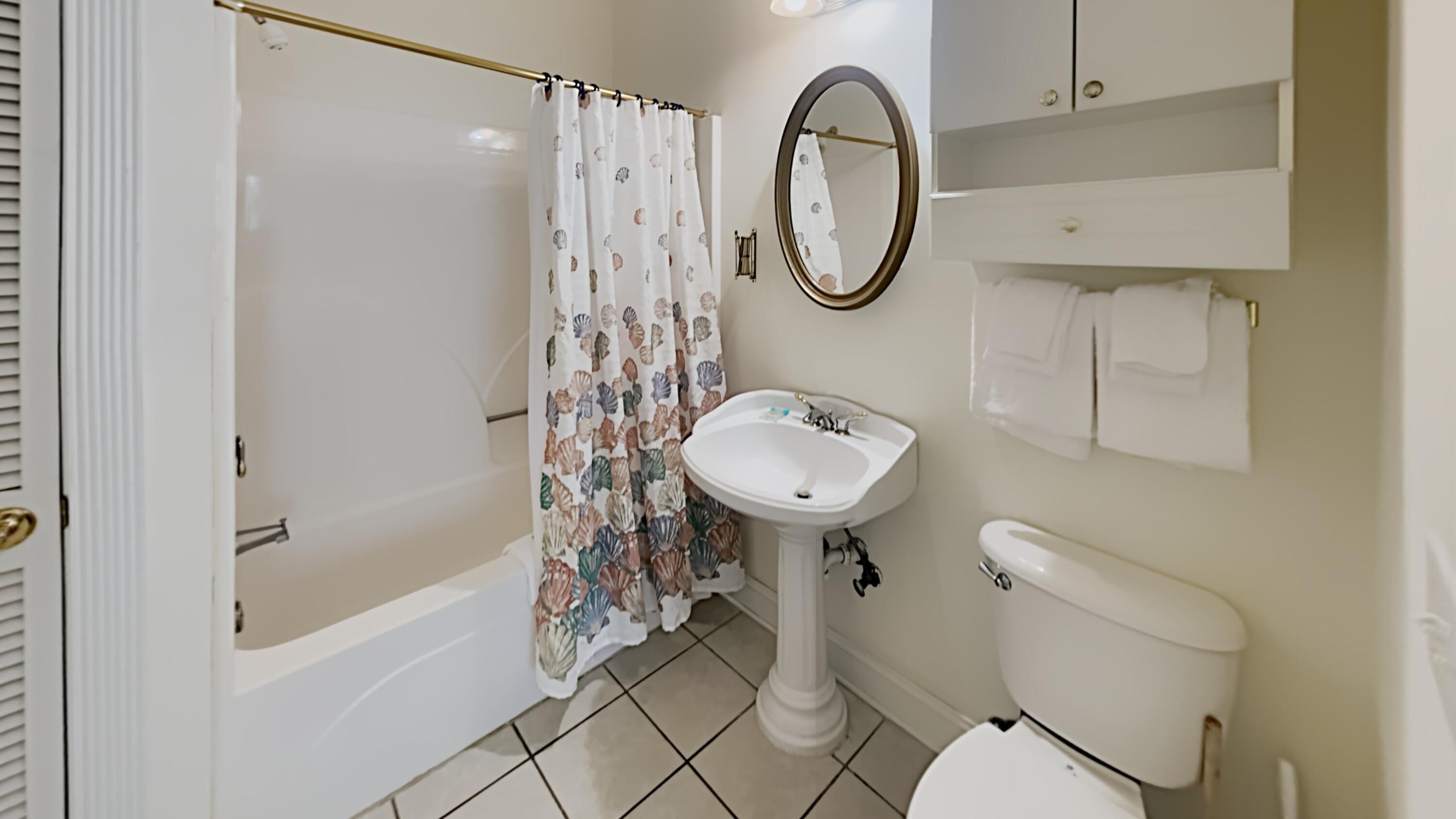 A bathroom with a bathtub, a sink, a toilet, and a mirror.
