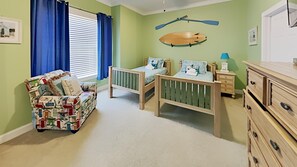 Une chambre d’enfant avec un lit, un petit canapé et une commode.