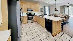 A modern kitchen with wooden cabinets, a stainless steel refrigerator, an oven, a microwave, and a dishwasher. - Tranquil Hideaway 4 Bdrm Condo in Avian Forest (Pawleys Island)