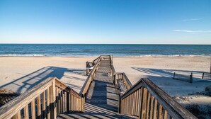 A wooden boardwalk leading to a beach with clear skies.