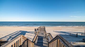 A wooden boardwalk leading to a beach with clear skies.