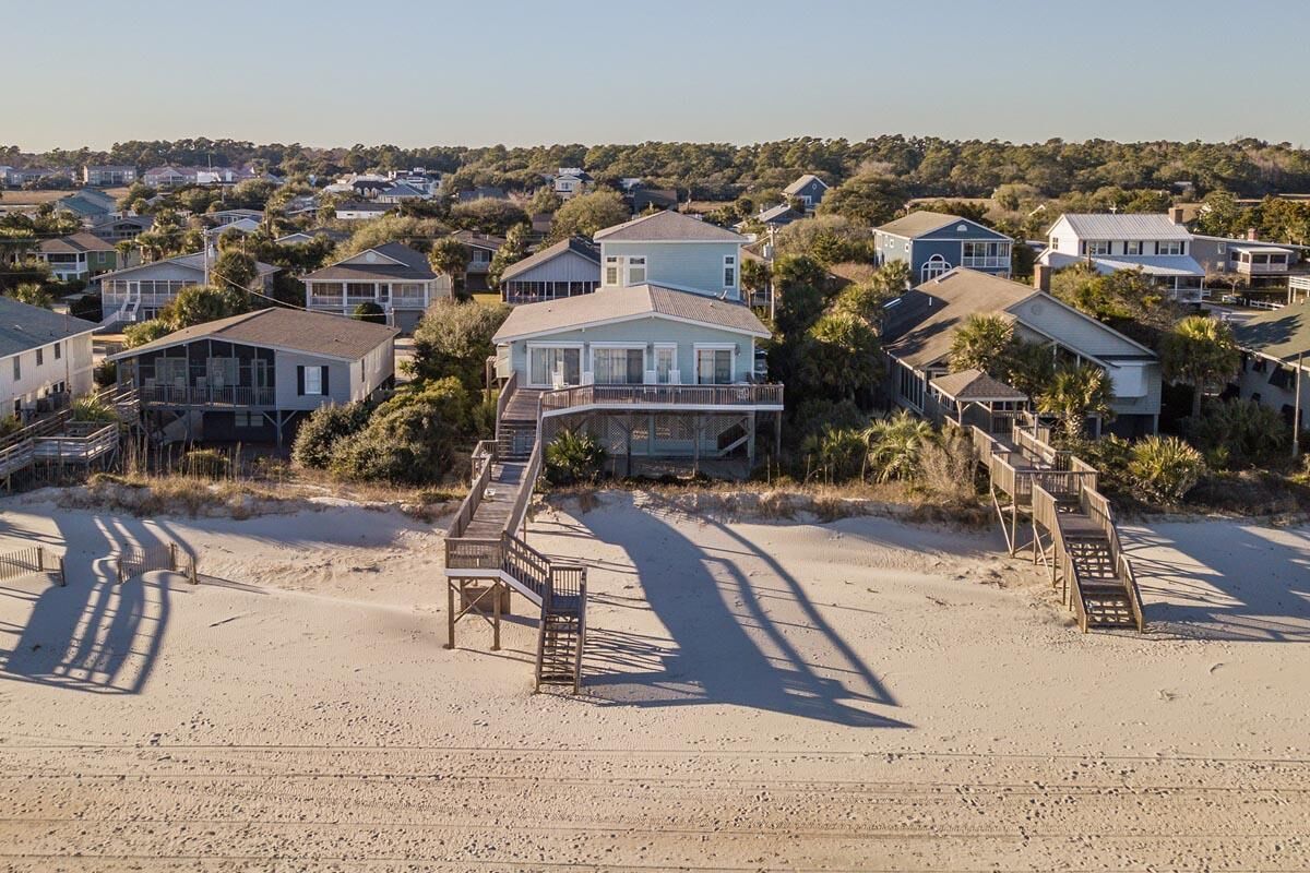A beachfront property with multiple houses, a wooden boardwalk, and a sandy beach.