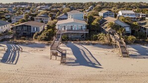 A beachfront property with multiple houses, a wooden boardwalk, and a sandy beach.