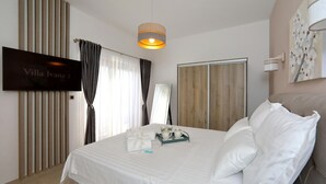 Et hotelværelse med en seng, et fjernsyn, et træskab og et billede på væggen.