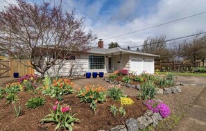 Une maison de plain-pied avec un jardin devant, où l’on trouve une variété de fleurs et d’arbustes.