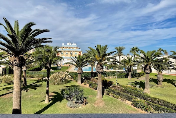 A hotel with a pool, palm trees, and a well-maintained garden.