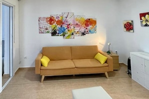 A living room with a sofa, a coffee table, a painting on the wall, a lamp, and a cabinet.