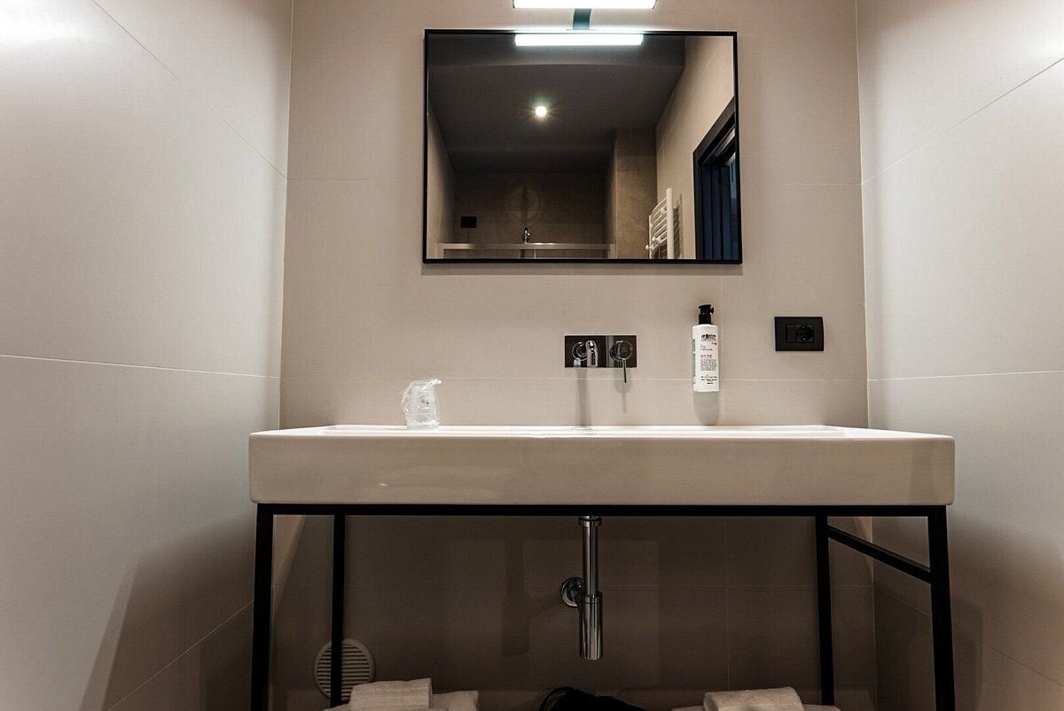 A modern bathroom with a large sink, a mirror, and a towel rack.