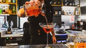 A bartender pouring a drink into a martini glass. - Arryvo (Lecce)