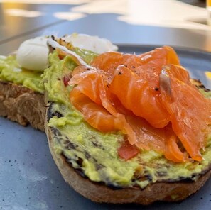 A sandwich with avocado, smoked salmon, and a boiled egg on a slice of bread.