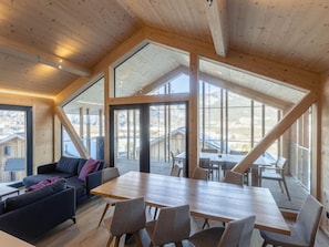 Um amplo quarto estilo loft com uma grande mesa de jantar de madeira, assentos confortáveis e janelas amplas com vista para os arredores.