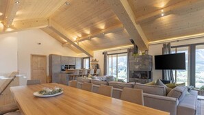 A spacious living area with a wooden dining table, sofas, and a stone fireplace.