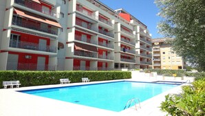 Ein mehrstöckiges Hotel mit Balkonen, einem Schwimmbad und einem gepflegten Garten.