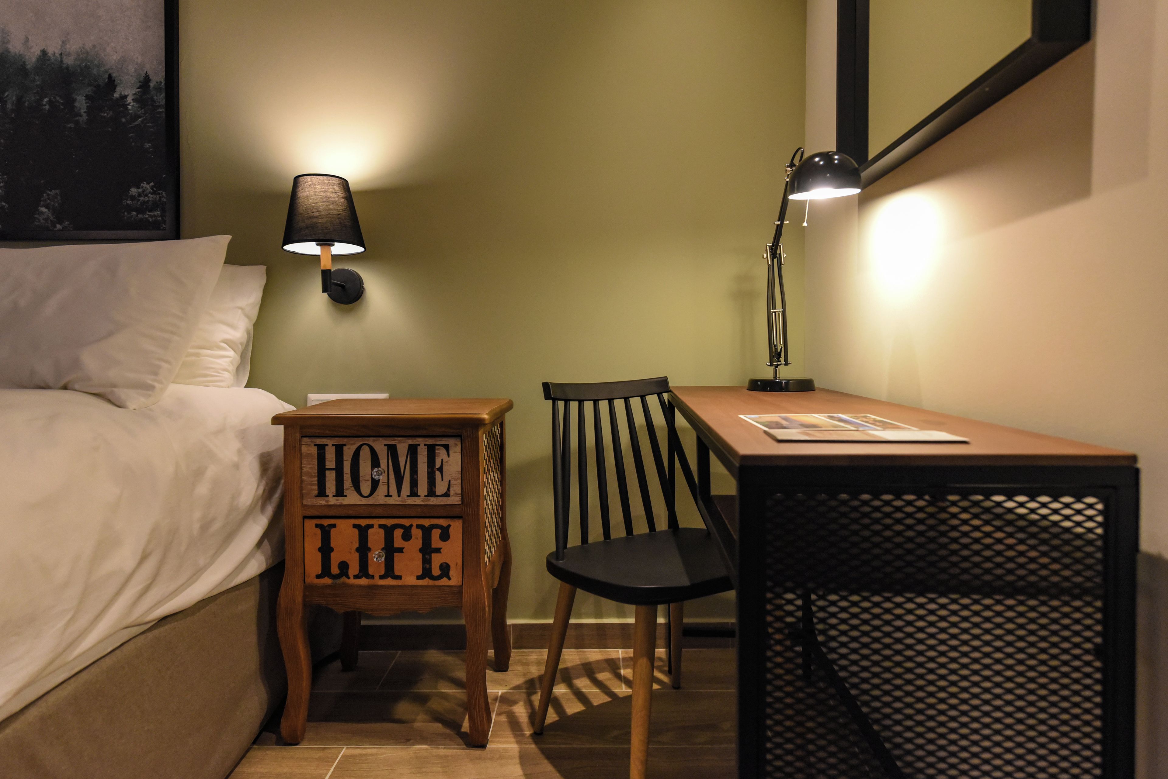 Una camera da letto con un letto, un comodino con una lampada, una sedia di legno e un tavolino.