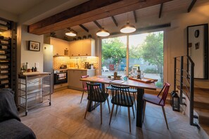 Une cuisine avec une table à manger, des chaises, un meuble à vin et une vue sur l’extérieur.