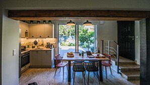 A kitchen with a dining area, a staircase, and a view of greenery outside.