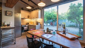 A modern kitchen with a dining area, large windows, and a view of the outdoors.