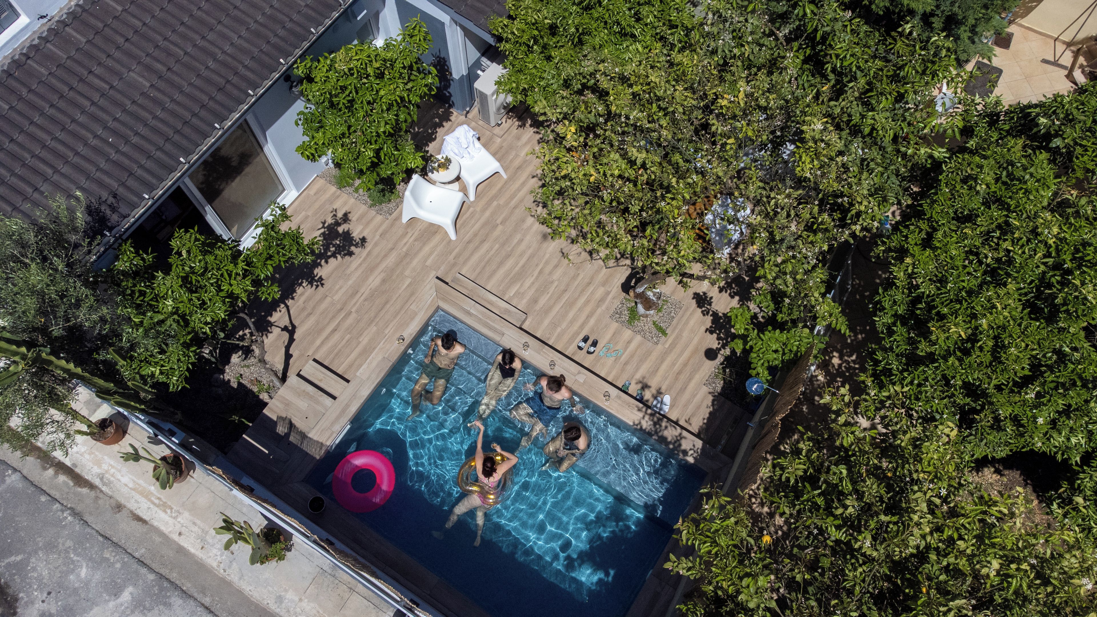 An aerial view of a swimming pool surrounded by greenery and a wooden deck.