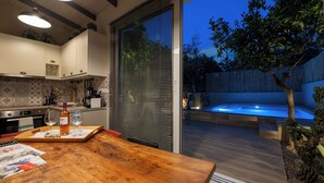 Une cuisine moderne avec une table à manger en bois, un jacuzzi et une porte-fenêtre coulissante donnant sur un jardin.