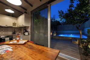 Een moderne keuken met een houten eettafel, een hottub en een schuifdeur naar een achtertuin.