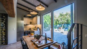 A modern kitchen with a dining area, large windows, and a wine rack.