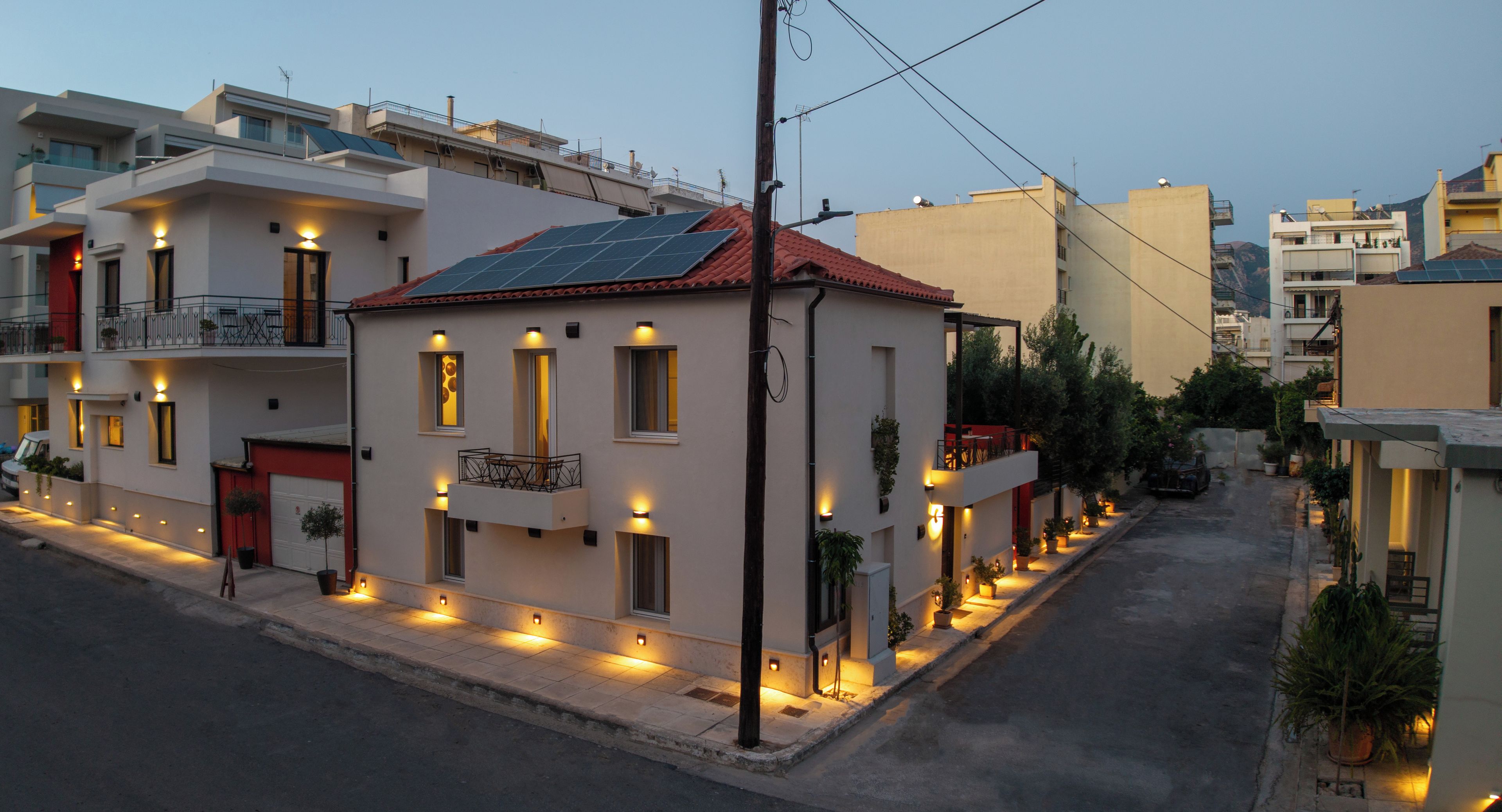 A modern building with solar panels, multiple balconies, and outdoor lighting along the street.