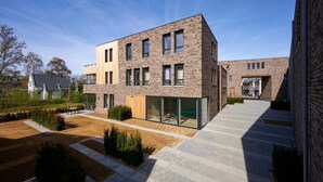 A modern building with a brick facade, large windows, and a flat roof. - Castellum Spa Apartment (Maastricht)
