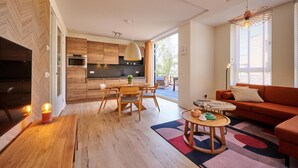A modern living room with a sofa, coffee table, and a dining area with wooden furniture. - Castellum Spa Apartment (Maastricht)