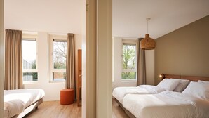 Quarto com duas camas, janelas amplas, piso de madeira e luminária pendente.