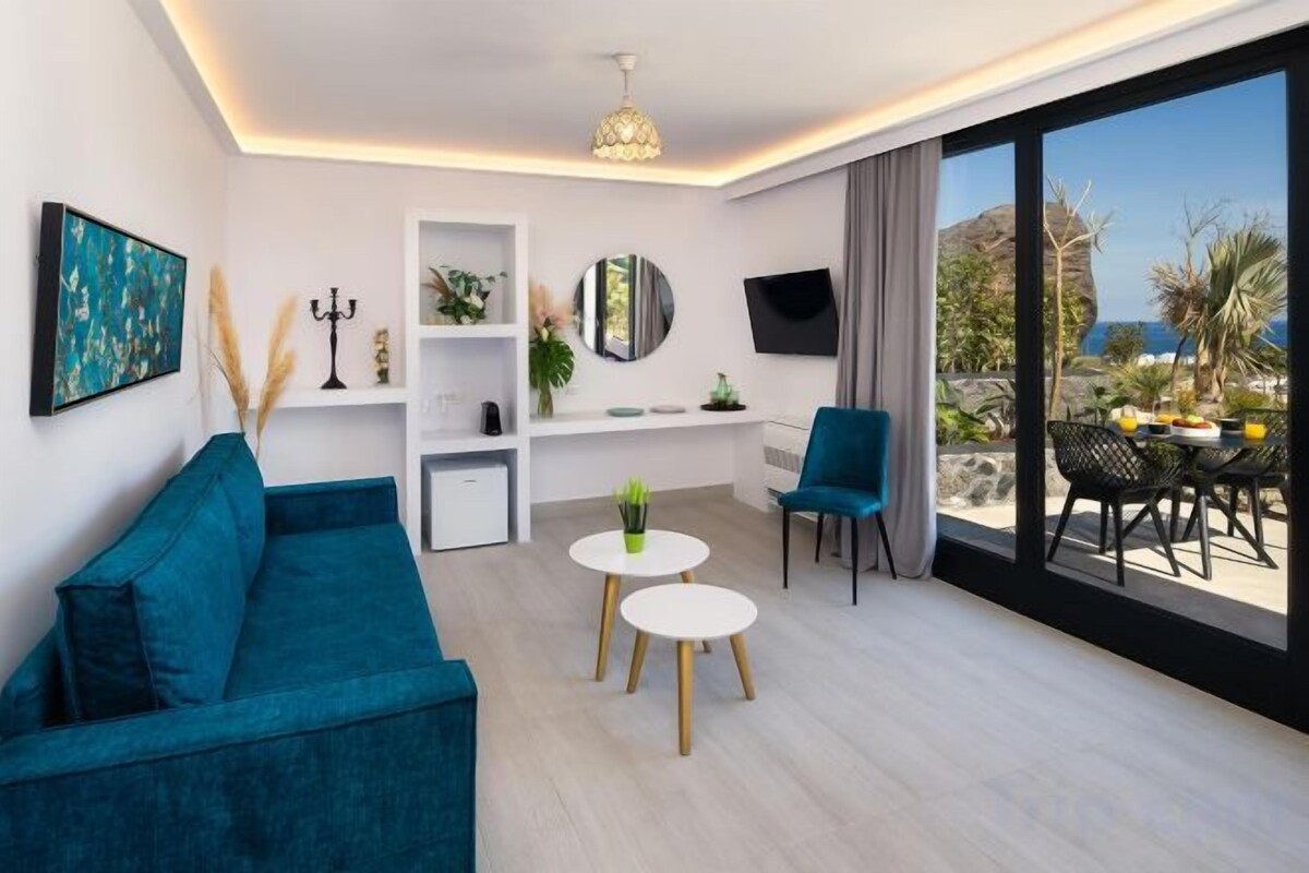 A modern living room with a sofa, a coffee table, a TV, and a balcony with a table and chairs.