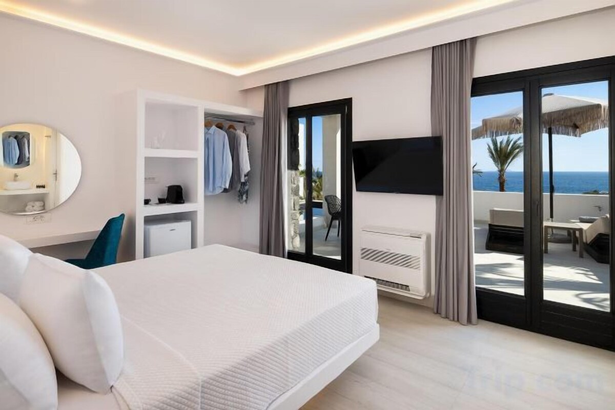 A hotel room with a bed, a wardrobe, a TV, and a balcony with a view.