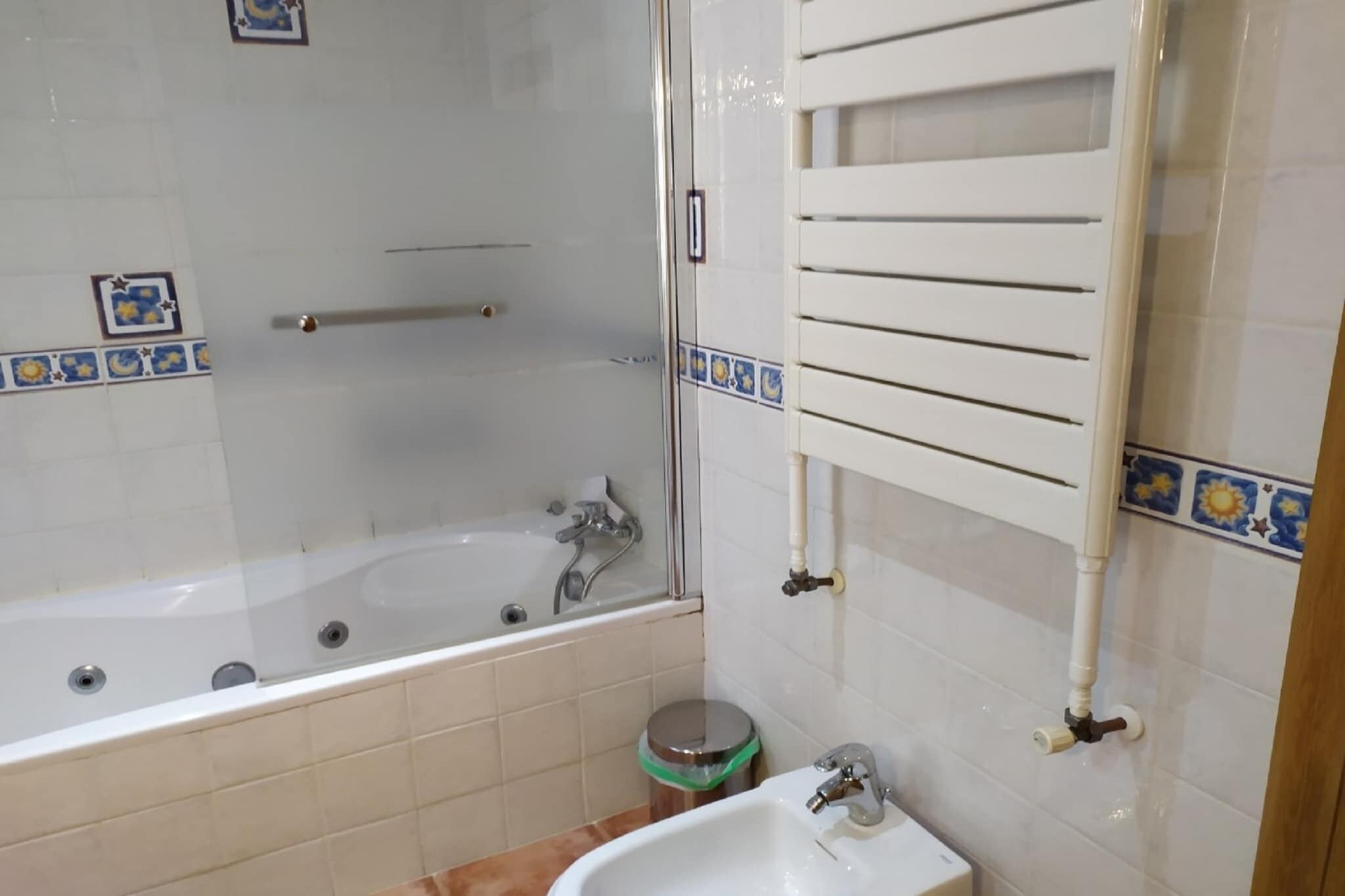 A bathroom with a glass-enclosed shower, a white sink, and a towel rack.