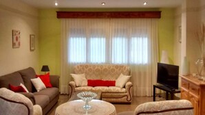 A living room with two sofas, a TV, and a small table with a glass object.