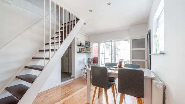 A modern interior with a staircase, wooden flooring, a dining area with chairs, and a window providing natural light. - Pretty Holiday Home in Schleiden with Balcony and Barbecue (Schleiden)