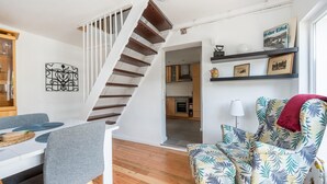 A modern living room with a staircase, a dining area, and a kitchen in the background. - Pretty Holiday Home in Schleiden with Balcony and Barbecue (Schleiden)
