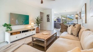 A modern living room with a sofa, coffee table, TV, and decorative items. - Sea Haven - Lennox Head (Lennox Head)
