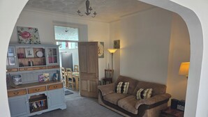A cozy living room with a sofa, a wooden cabinet, and a dining area. - 6 Guests-free Public Parking-5 Min to Beach (Porthcawl)