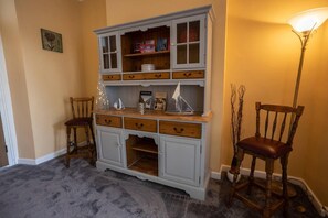 Cozy retreat with a light cabinet, comfortable chair, and warm floor lamp.