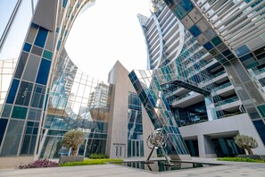 Un bâtiment moderne aux façades vitrées réfléchissantes, avec une sculpture imposante en premier plan.