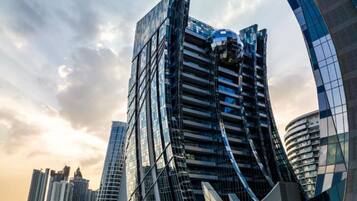 A modern high-rise building with a curved glass facade, surrounded by other high-rise buildings.