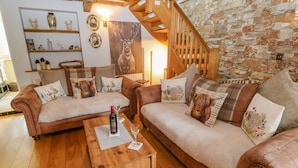 A cozy living room with two brown leather sofas, a wooden coffee table, and a stone wall. - Eden Cottage (Appleby-in-Westmorland)