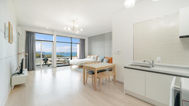 A modern hotel room with a balcony, a kitchenette, and a large window offering a sea view. - Yangyang In Memory Pension (Yangyang)