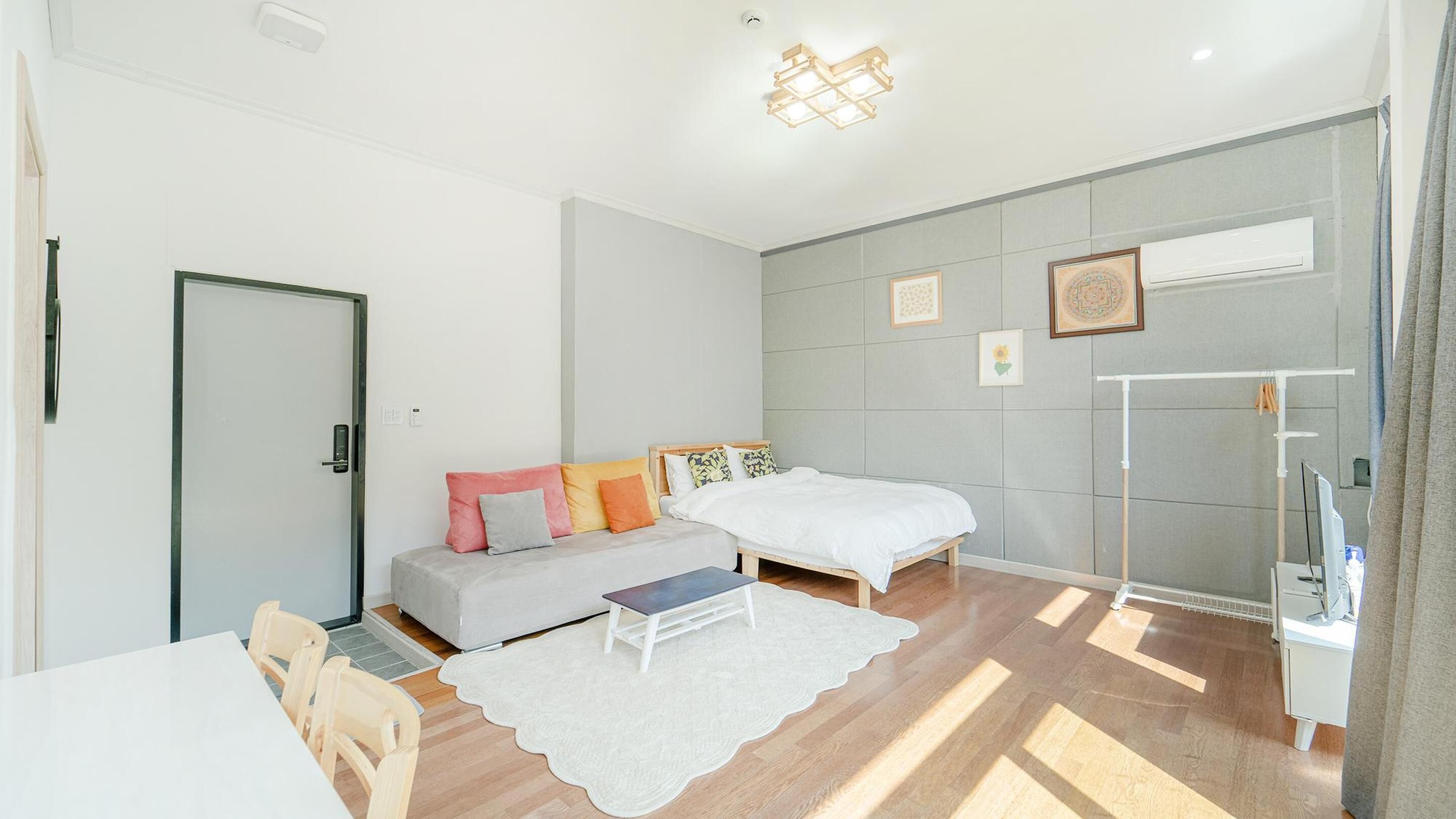 A modern bedroom with a bed, a sofa, a desk, and a chair.