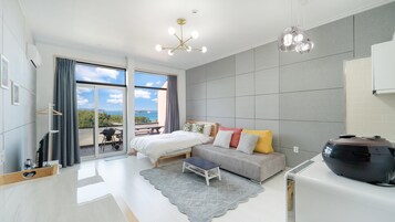 A modern bedroom with a bed, a sofa, a small table, and a large speaker.