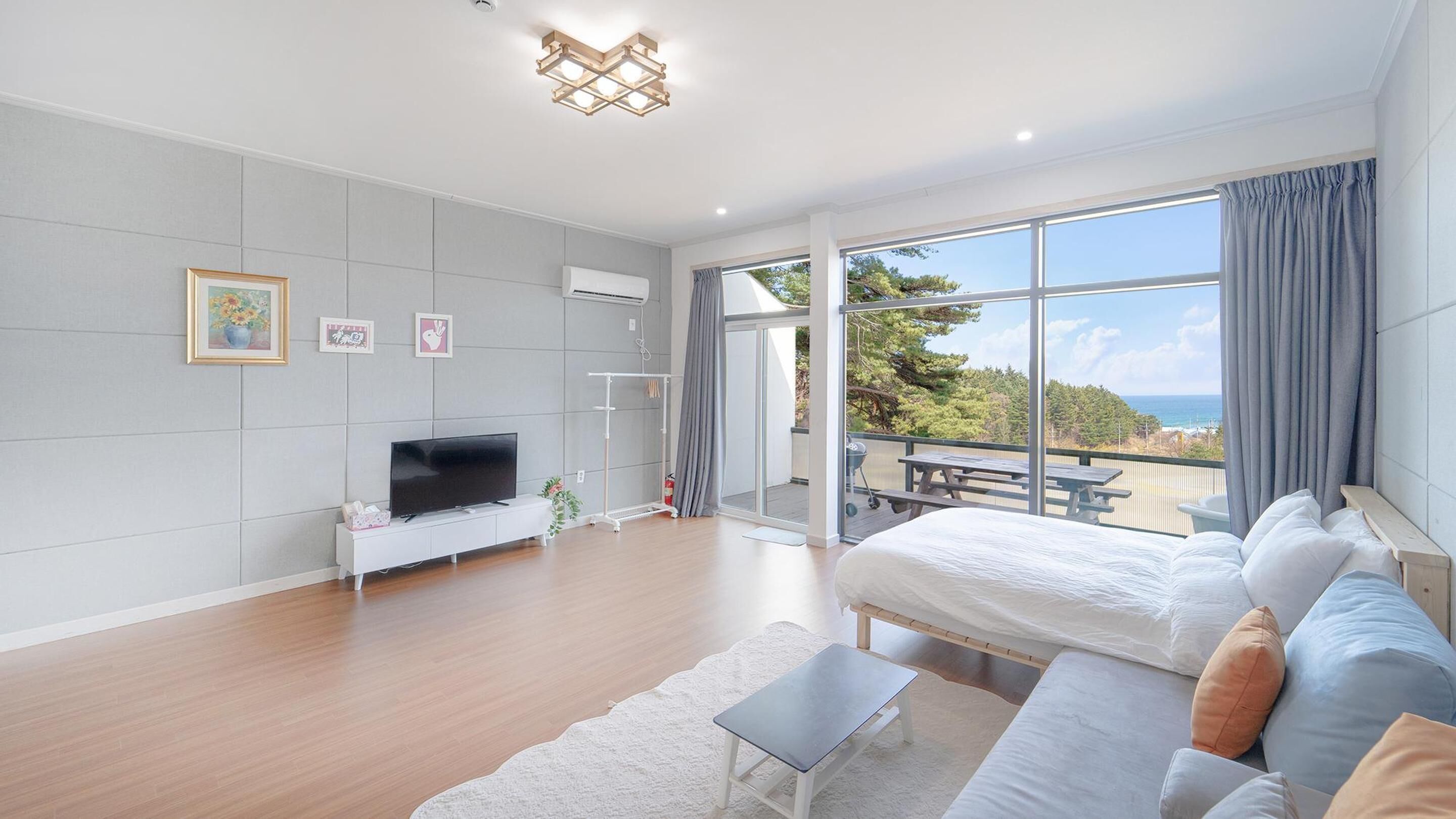 Quarto moderno com uma cama grande, televisão e varanda com vista para o oceano.