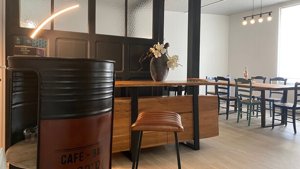 A café with a wooden table, a barista counter, and a seating area with chairs.