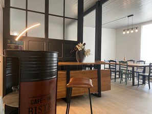Ein Café mit Holztisch, einer Barista-Theke und einer Sitzgelegenheit mit Stühlen.