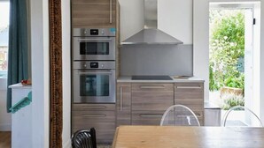 Une cuisine moderne dotée d’appareils électroménagers en acier inoxydable, de meubles en bois et offrant une vue sur la verdure environnante.