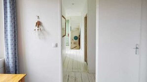 Un couloir au plancher de bois menant à une pièce dotée d’une porte.