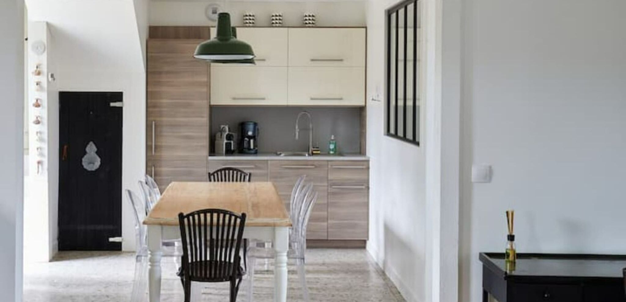 A modern kitchen with white cabinets, a wooden dining table, and black chairs.
